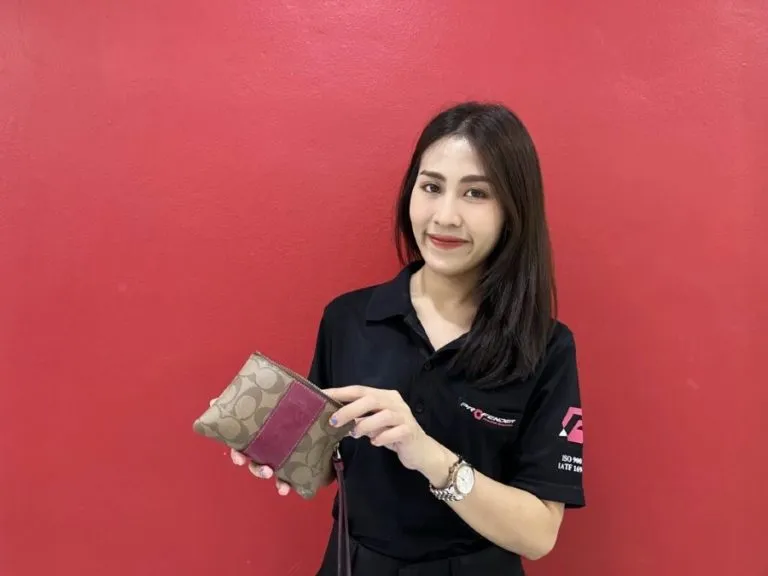 พนักงาน Profender ผู้หญิงถือกระเป๋าเงินยี่ห้อ coach พื้นหลังสีแดง