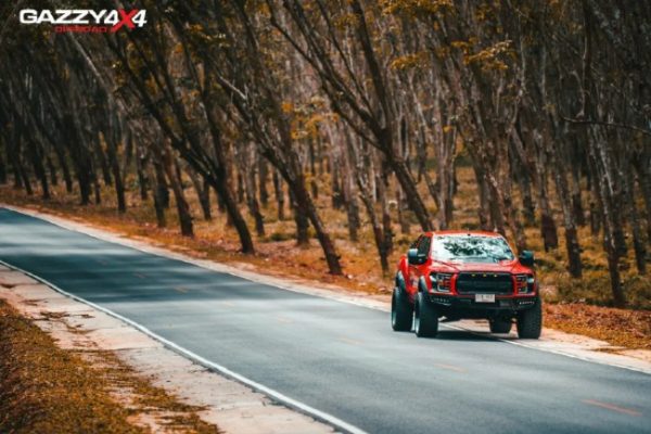 รถกระบะสีแดงกำลังขับบนถนน