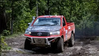 รถกระบะToyota Hilux สีแดง แต่งยกสูงสไตล์ออฟโรด กำลังขับลุยป่า