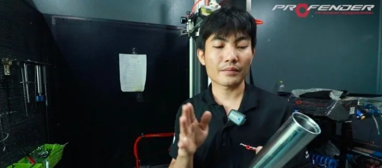 พนักงานชายกำลังมองชิ้นส่วนของโช๊คอัพProfender เป็นส่วนกระบอกสีเงิน